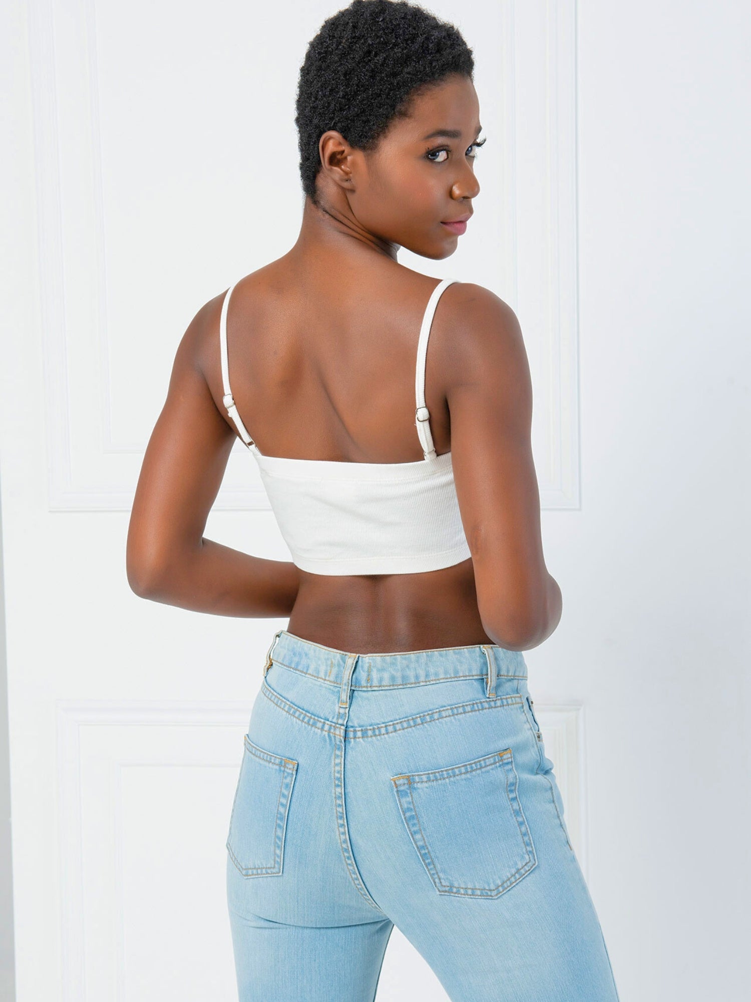 Woman in a white Atwood Camisole and light blue jeans, stylishly viewed from behind