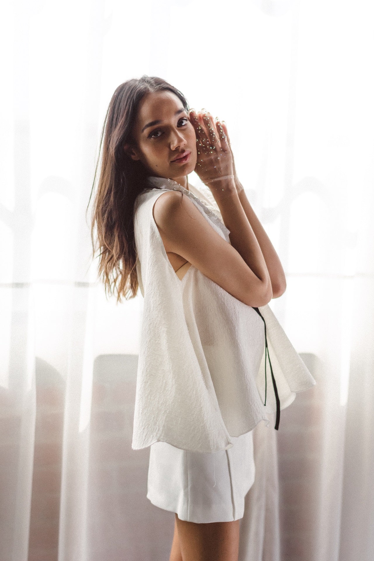 Woman modeling The Beaded Botanic Top by Sister Jane, hands near her face