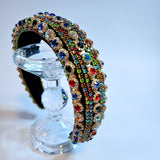 Ornate jewel-encrusted crown headband on a clear glass bust for elegant gown styling