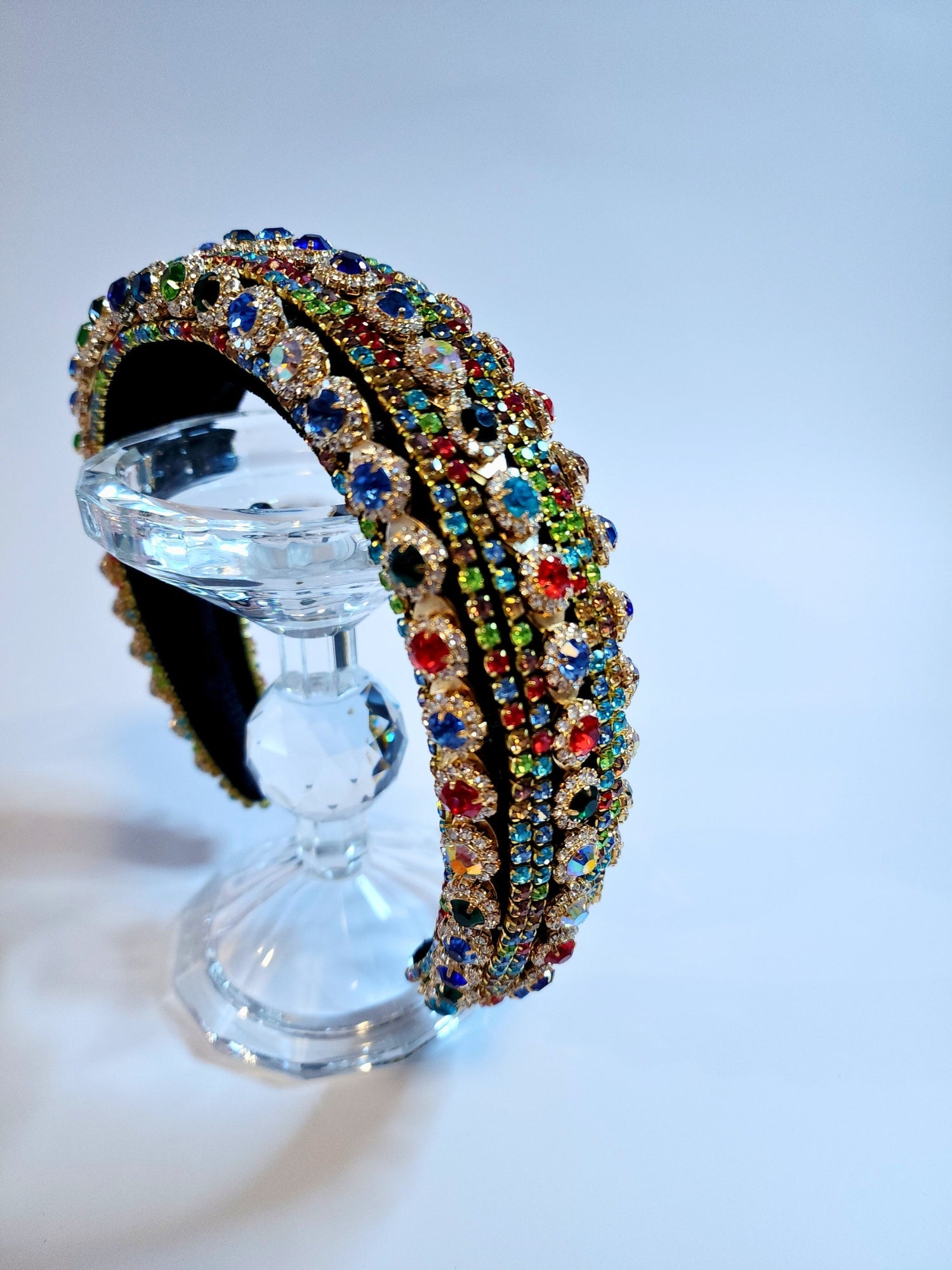 Ornate jewel-encrusted crown headband on a clear glass bust for elegant gown styling