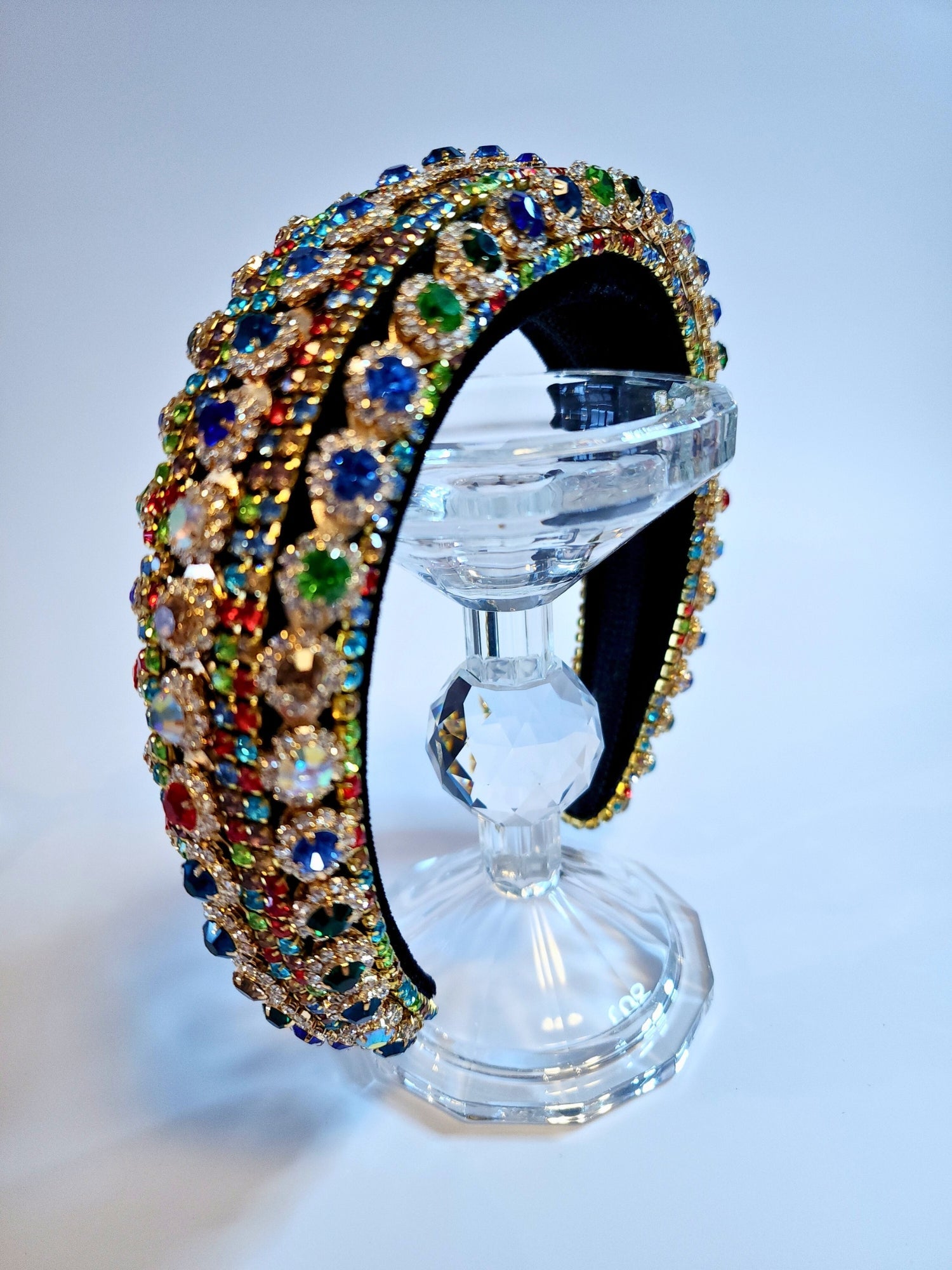 Ornate jewel-encrusted crown headband displayed elegantly on a clear stand