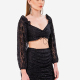 Woman in a black magic lace crop top and mini skirt showcasing elegance and style