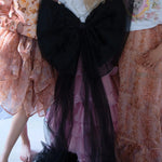 The Black Swan Grand Bow Belt styled in a dreamy ensemble, featuring oversized black tulle bow with long trailing ends over a pink ruffled skirt.