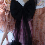 The Black Swan Grand Bow Belt styled in a dreamy ensemble, featuring oversized black tulle bow with long trailing ends over a pink ruffled skirt.