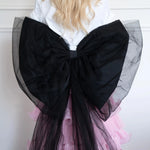 The Black Swan Grand Bow Belt in voluminous black tulle and satin, styled over a pink ruffled skirt for a dramatic fashion statement.