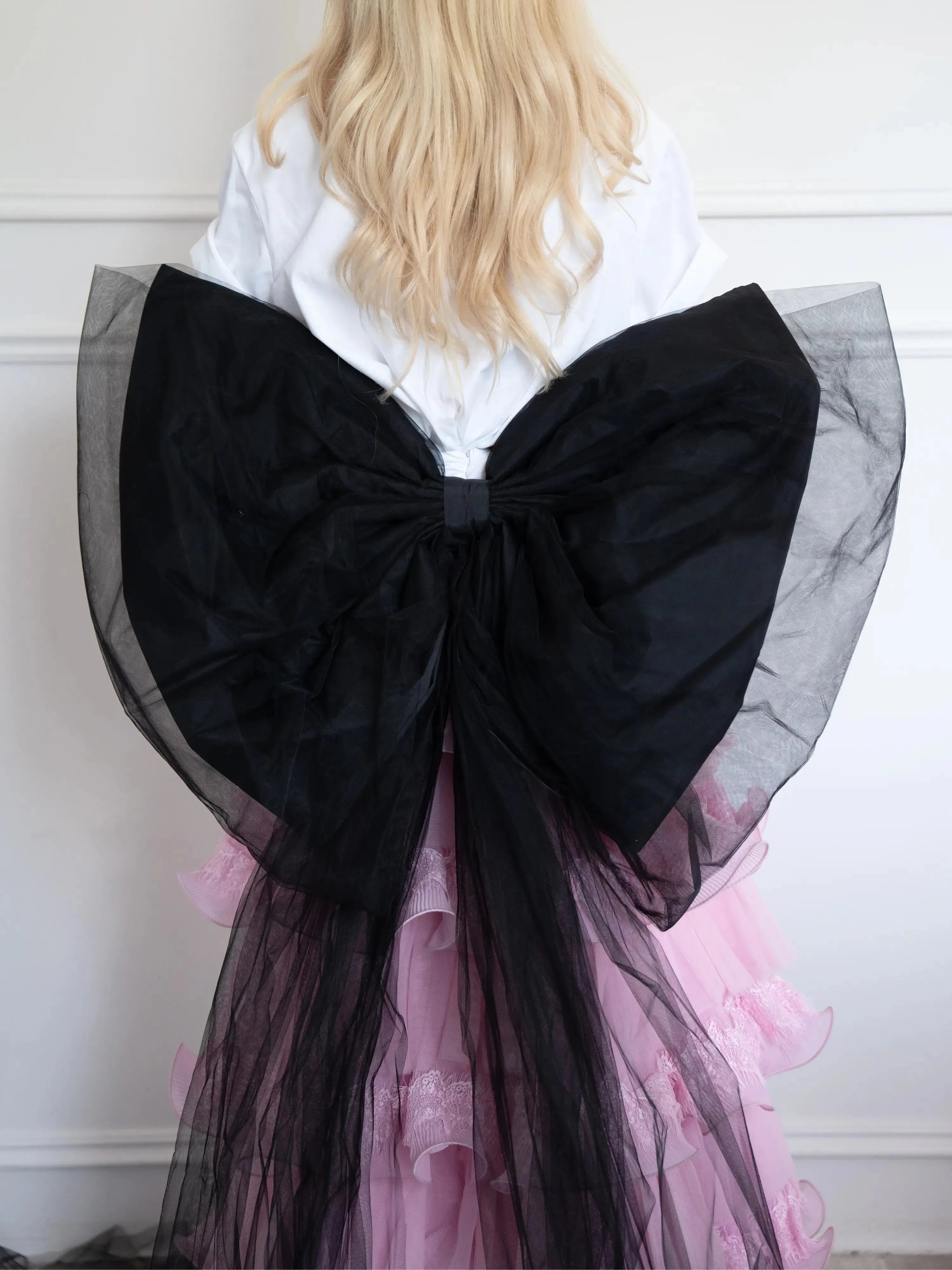 The Black Swan Grand Bow Belt in voluminous black tulle and satin, styled over a pink ruffled skirt for a dramatic fashion statement.