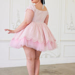 A back view of a woman wearing a pink cotton mini dress with short sleeves and a tulle skirt to create a dreamy puff dress.