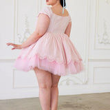 A back view of a woman wearing a pink cotton mini dress with short sleeves and a tulle skirt to create a dreamy puff dress.