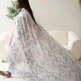 A plus-sized model wearing the blossom pink cotton mini dress and an oversized floral printed cape.