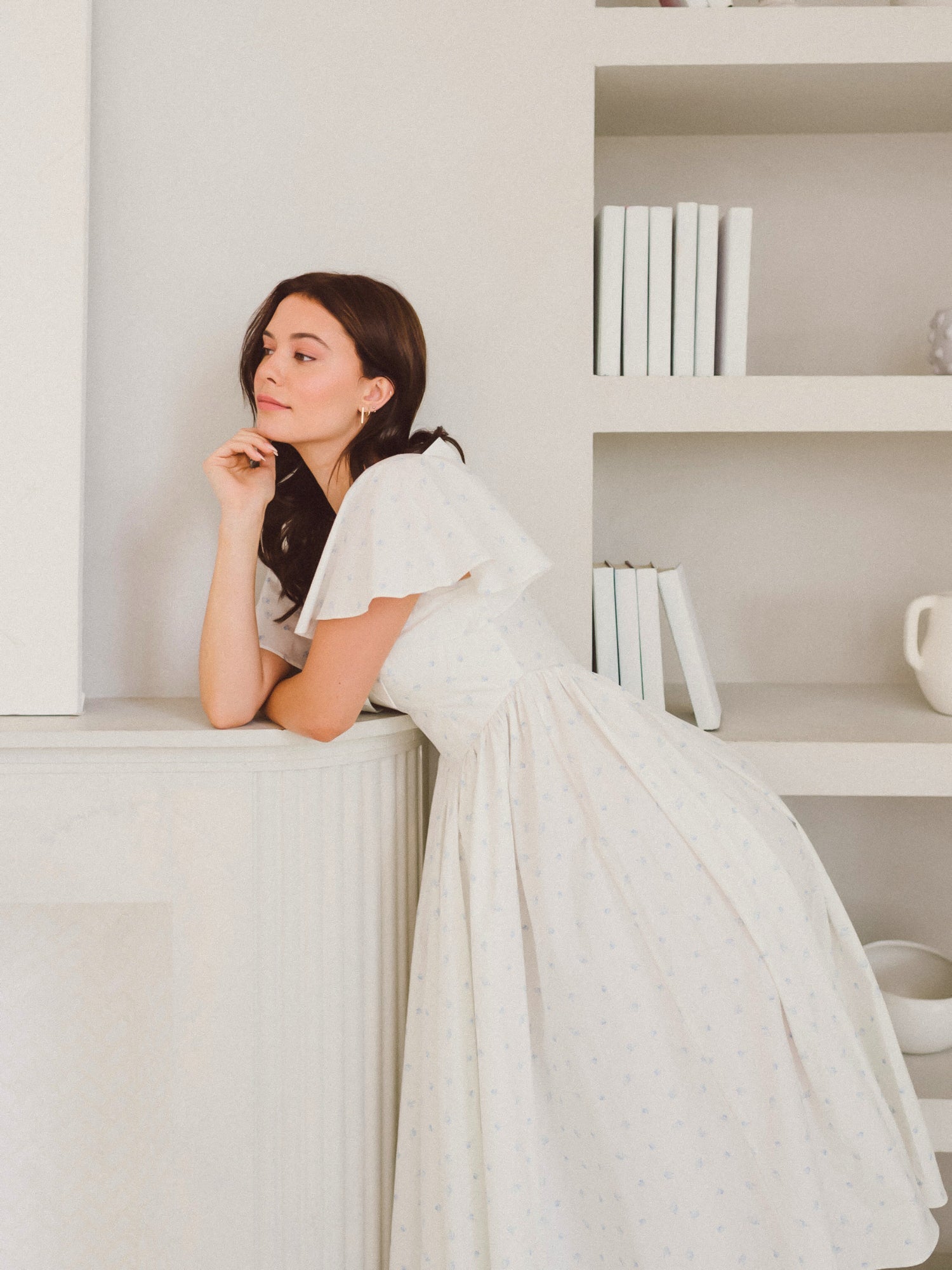 Woman in a white dress leaning on a shelf in Blue Blooms French Milkmaid Dress