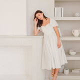 Woman in a white off-shoulder dress, showcasing the Blue Blooms French Milkmaid Dress