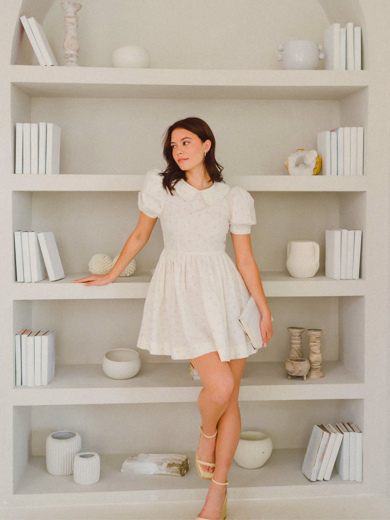 Woman in a short white puffed sleeve dress from Blue Blooms Lamb Mini Dress collection