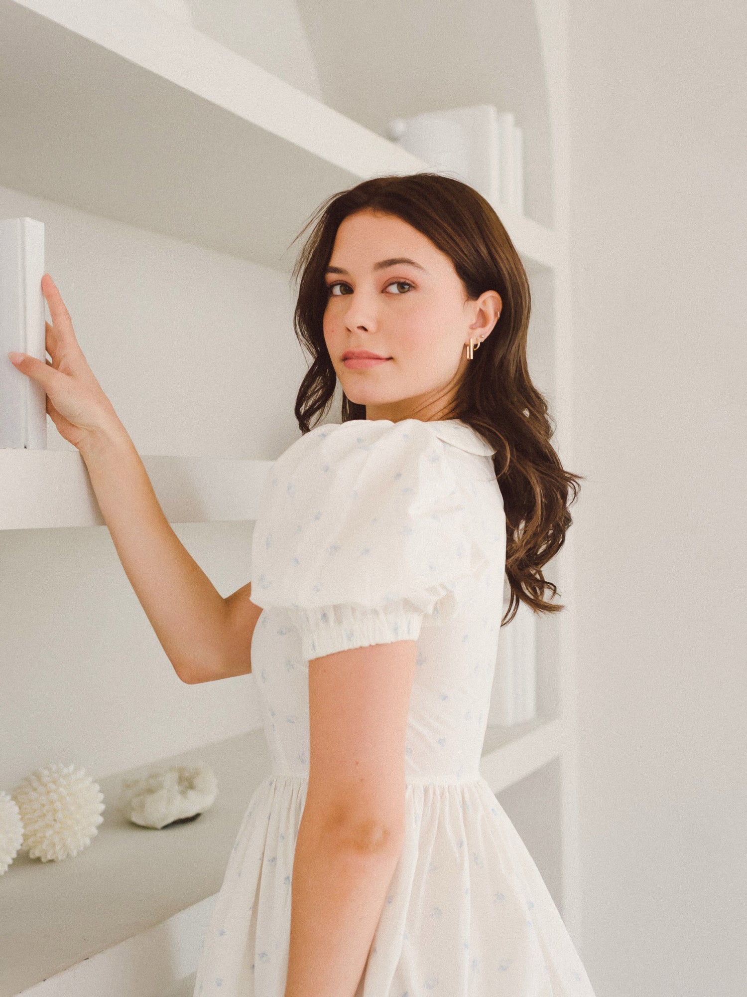 Woman in a white dress with dark hair modeling the Blue Blooms Lamb Mini Dress