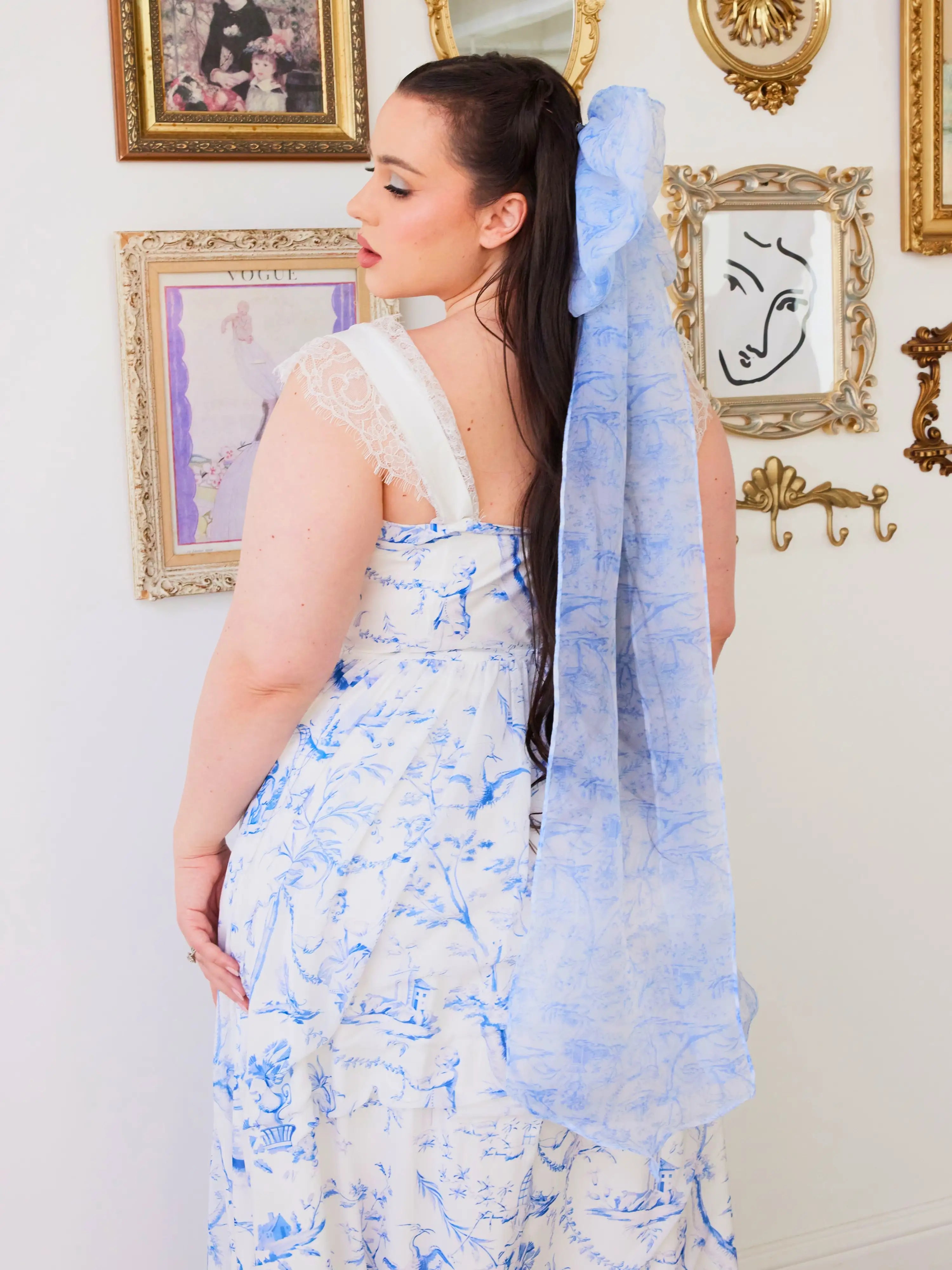 Woman in a flowing blue toile gown with a long train, showcasing blue toile print elegance