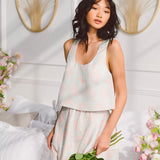 Woman in a white outfit showcasing the Candy Floss La Marais Tank Top Blouse with pink flowers