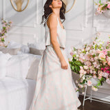 Woman in a flowing white dress showcases the Candy Floss Tropez Maxi Skirt in a romantic setting