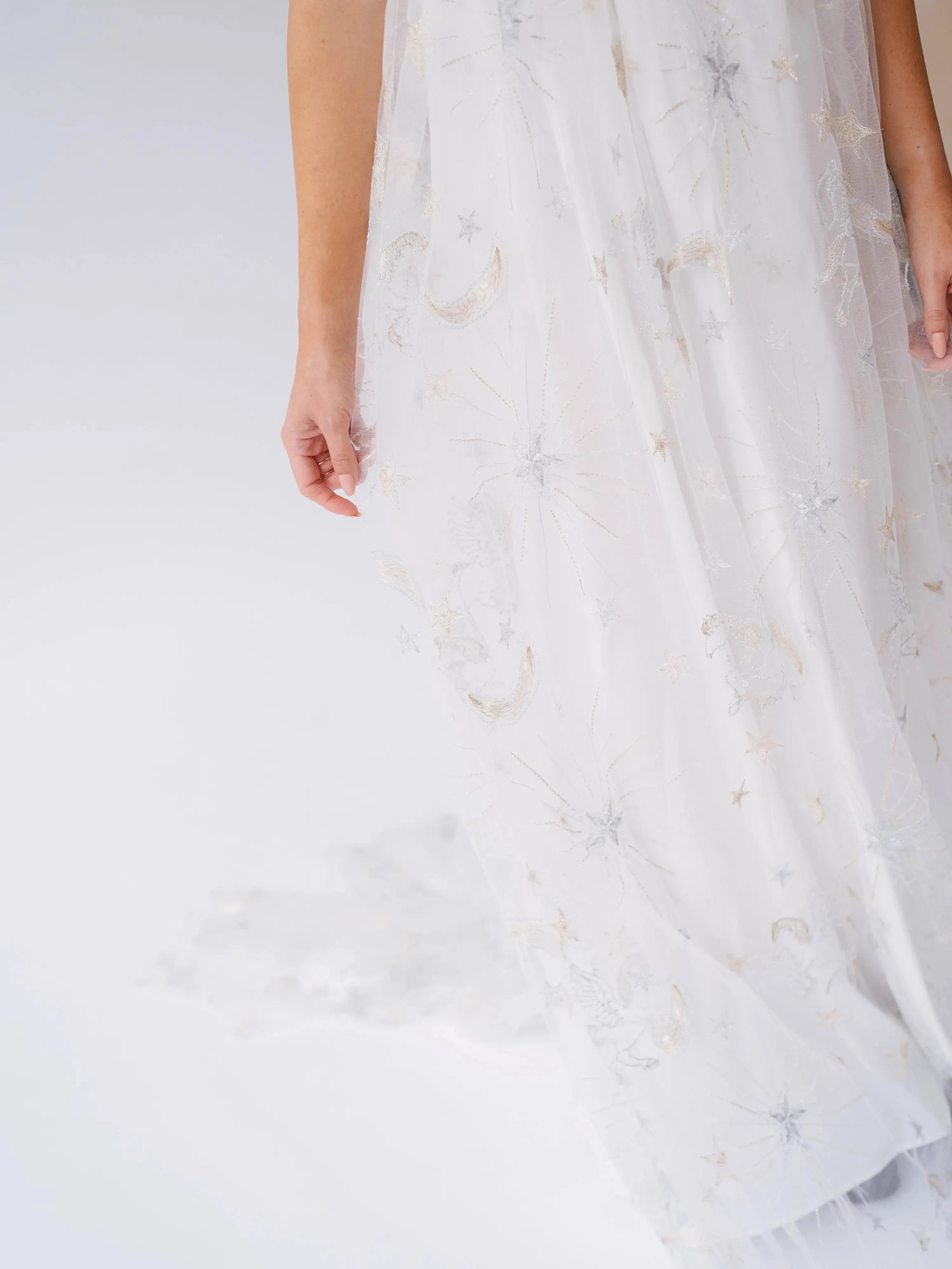 Detail of the Celestial Veil Dauphine Lace Gown's embroidered stars and moons on sheer tulle. Perfect for fantasy-inspired or bridal fashion.
