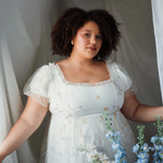 The Celestial Veil Dauphine Lace Gown with short puff sleeves and ruffled neckline, styled with soft drapery and florals. Ideal for Bridgerton-inspired weddings.