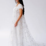 A flowing white lace gown with delicate floral appliques and short sleeves.