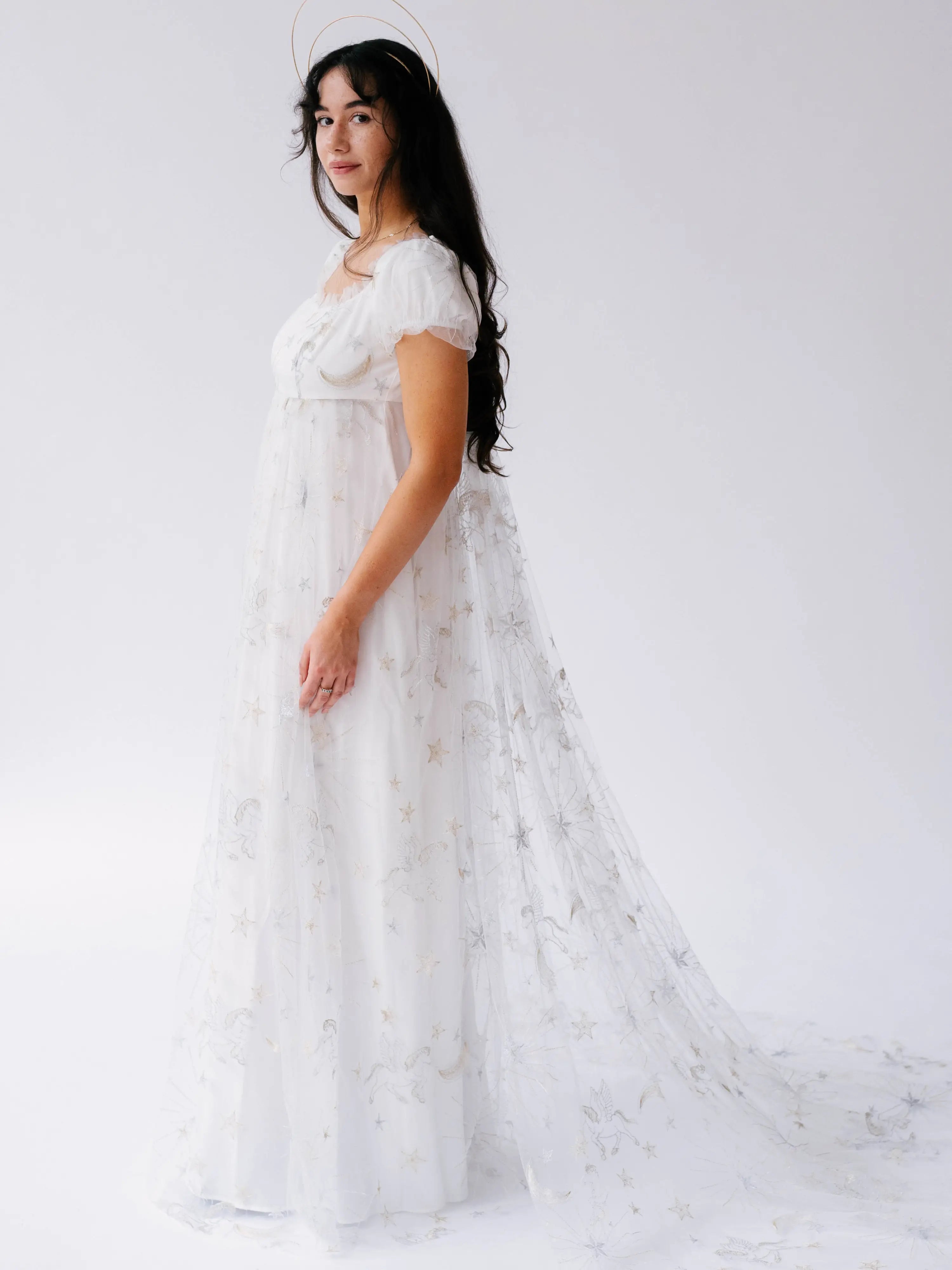 A flowing white lace gown with delicate floral appliques and short sleeves.