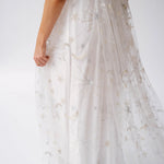 White lace gown with delicate silver star embellishments flowing down the skirt.