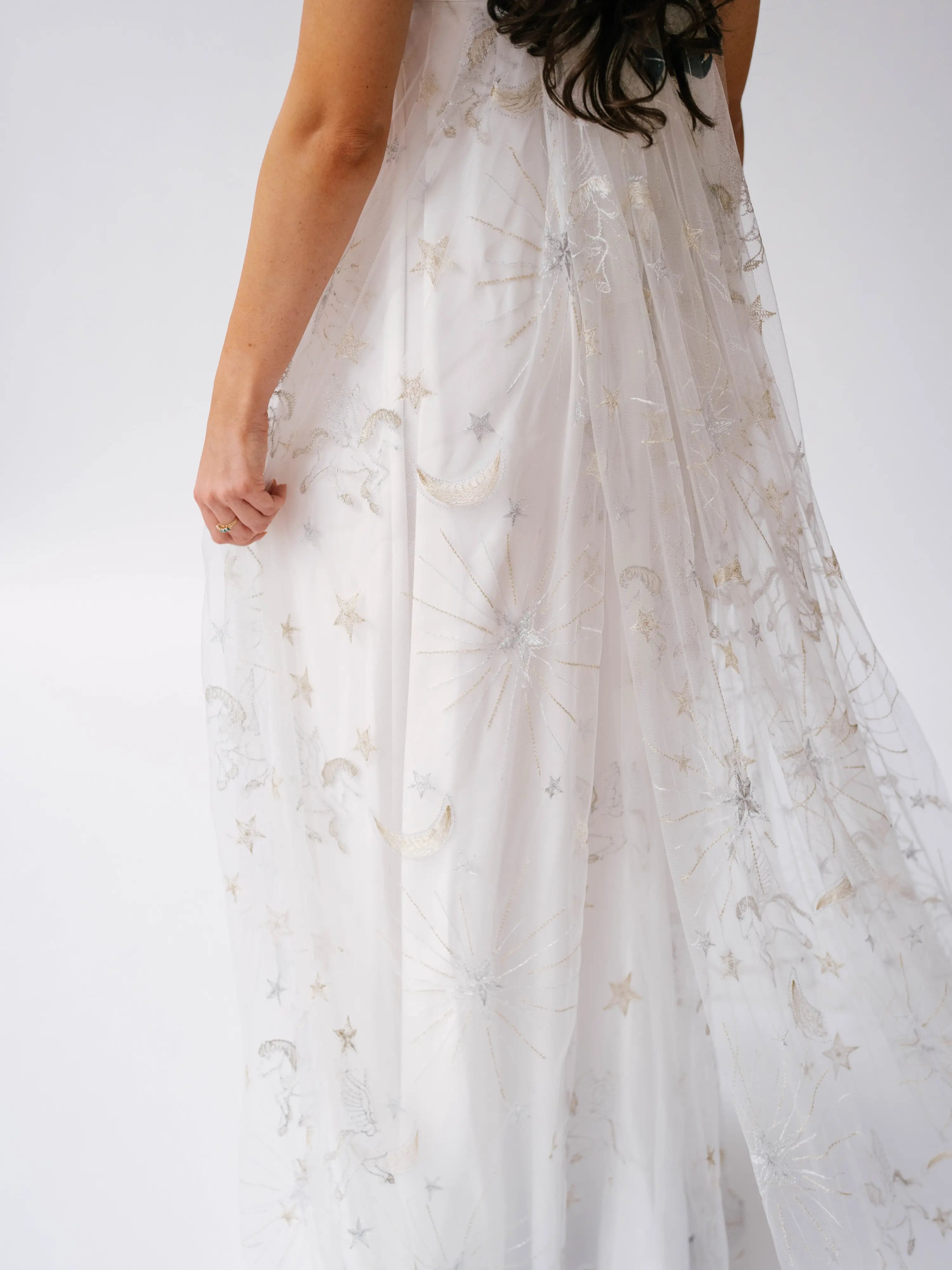 White lace gown with delicate silver star embellishments flowing down the skirt.