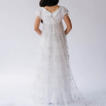 White lace gown with delicate star and moon details and cap sleeves photographed from behind.