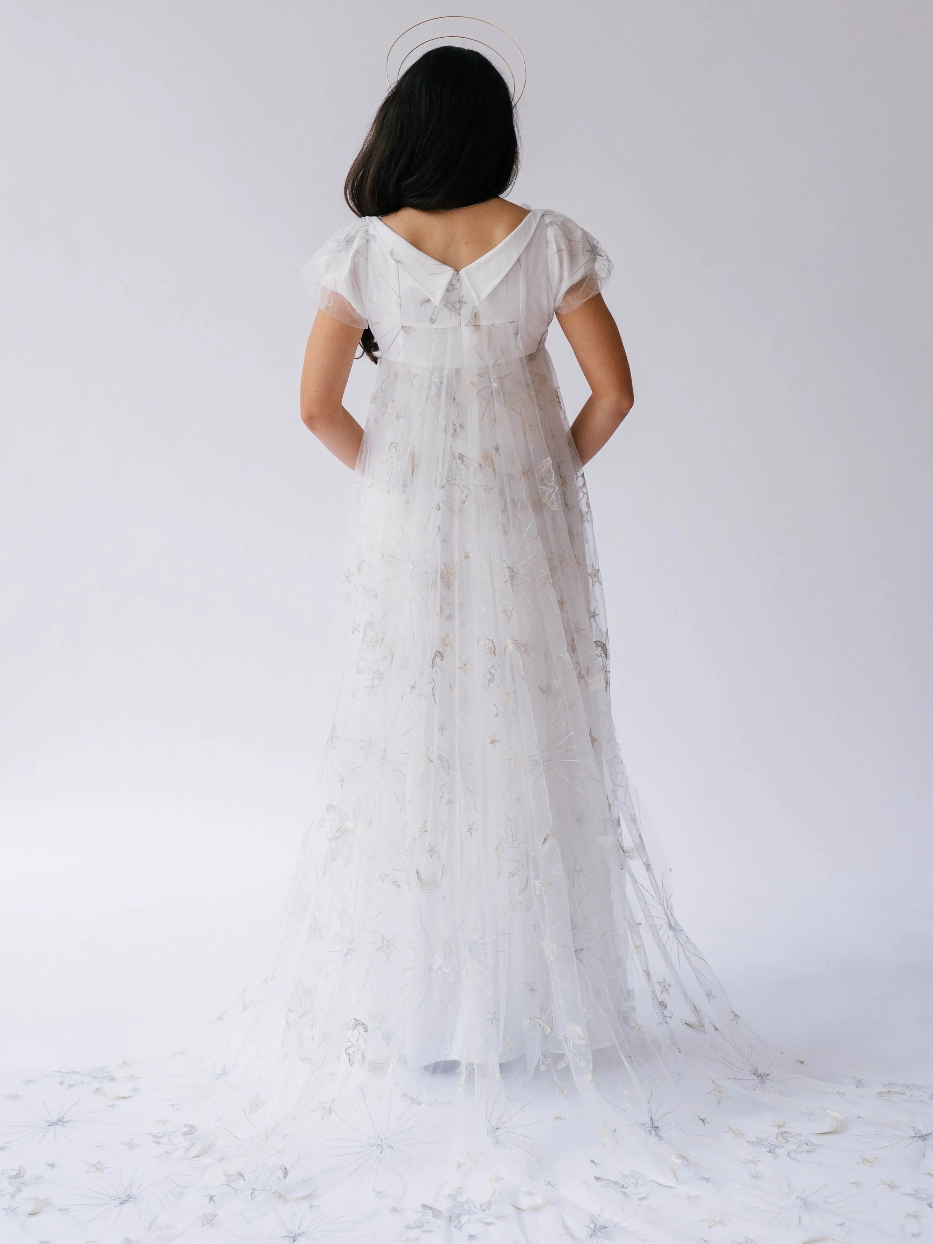 White lace gown with delicate star and moon details and cap sleeves photographed from behind.