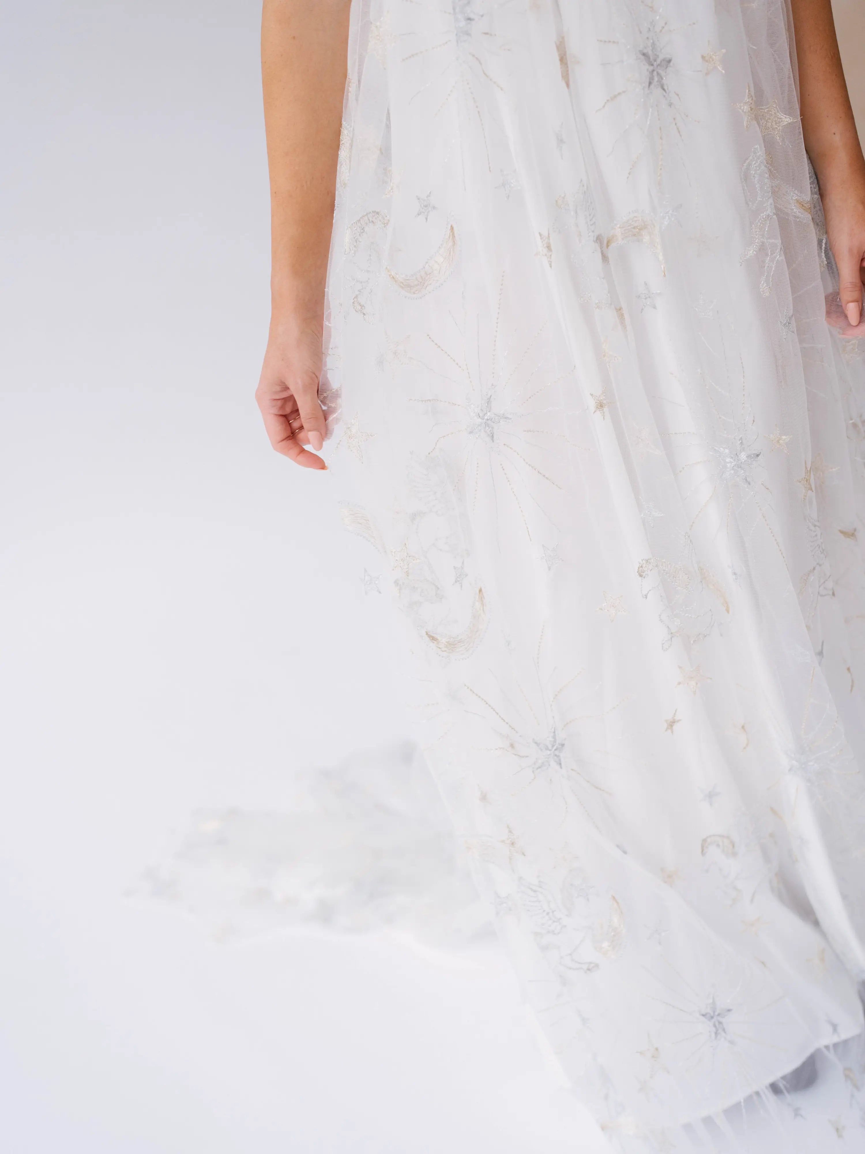 White fabric with delicate gray moon and star patterns on a lace gown.