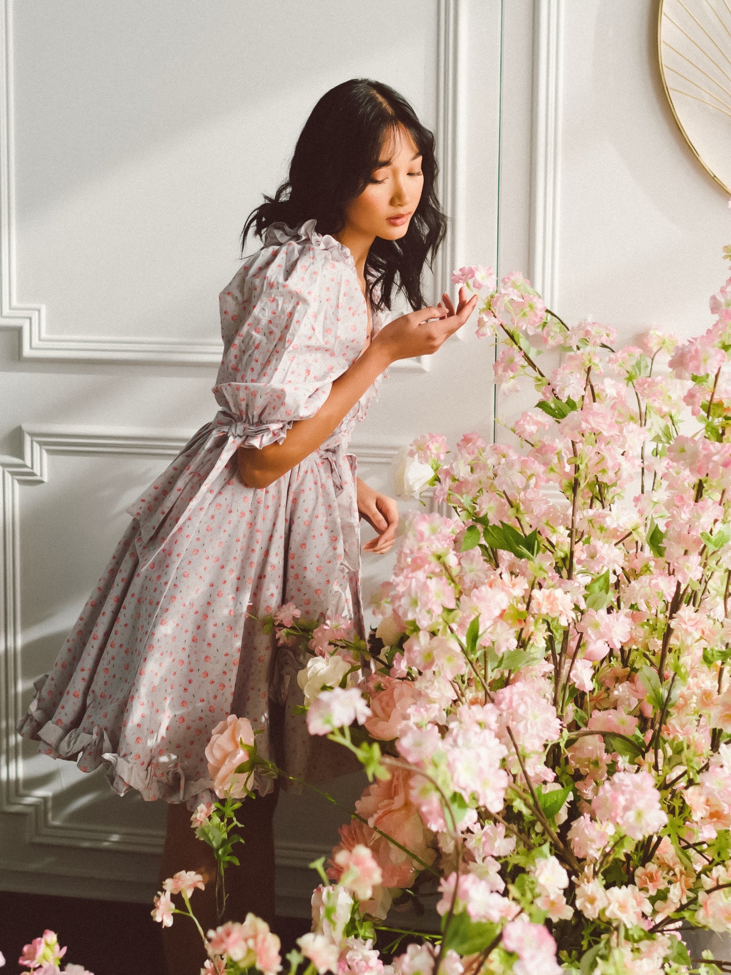 Woman in a floral dress arranging pink blossoms in the Chateau Rose Marie Dress