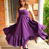 Woman wearing a flowing purple cotton everyday dress with a ruffled hem