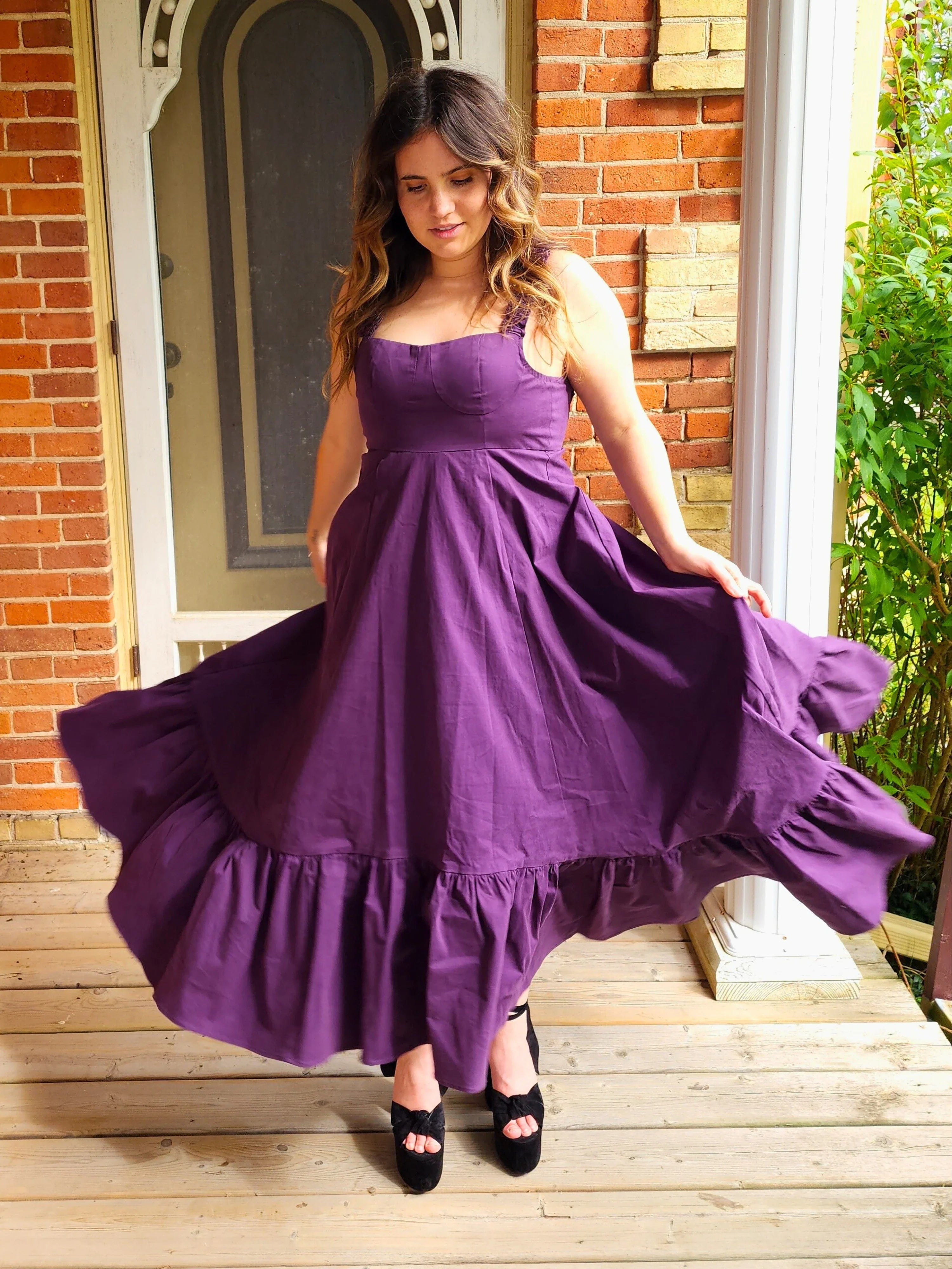 Woman wearing a flowing purple cotton everyday dress with a ruffled hem