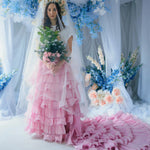 A woman wearing the dahlia pink ruffle skirt with floral decorations and a veil.