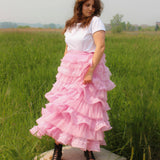 Woman in a white top models the Dahlia Ruffle Skirt with voluminous pink ruffles