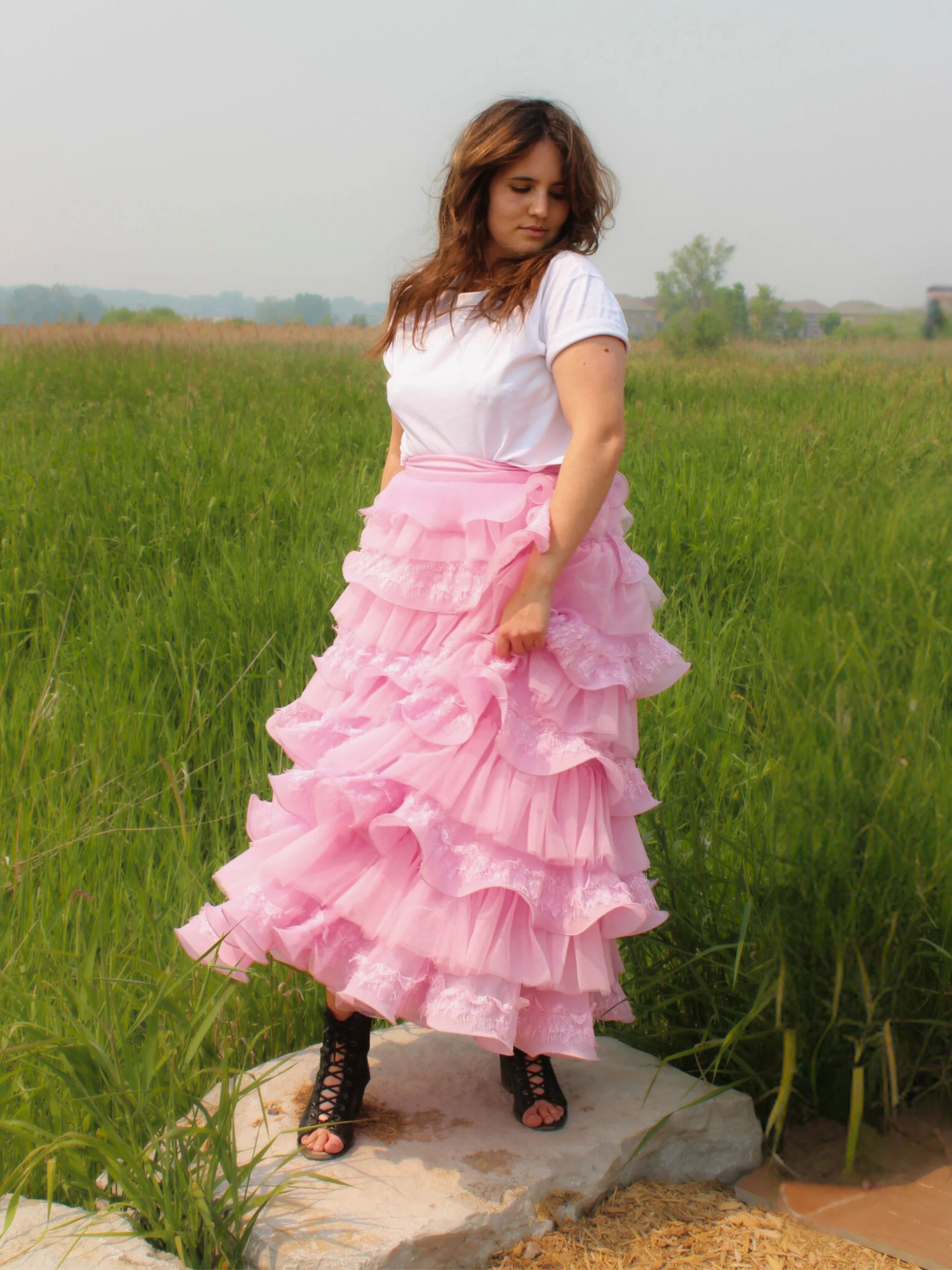 Woman in a white top models the Dahlia Ruffle Skirt with voluminous pink ruffles