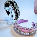 Both pink and black diamond goddess headbands displayed on a crystal stand.