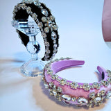 Both pink and black diamond goddess headbands displayed on a crystal stand.