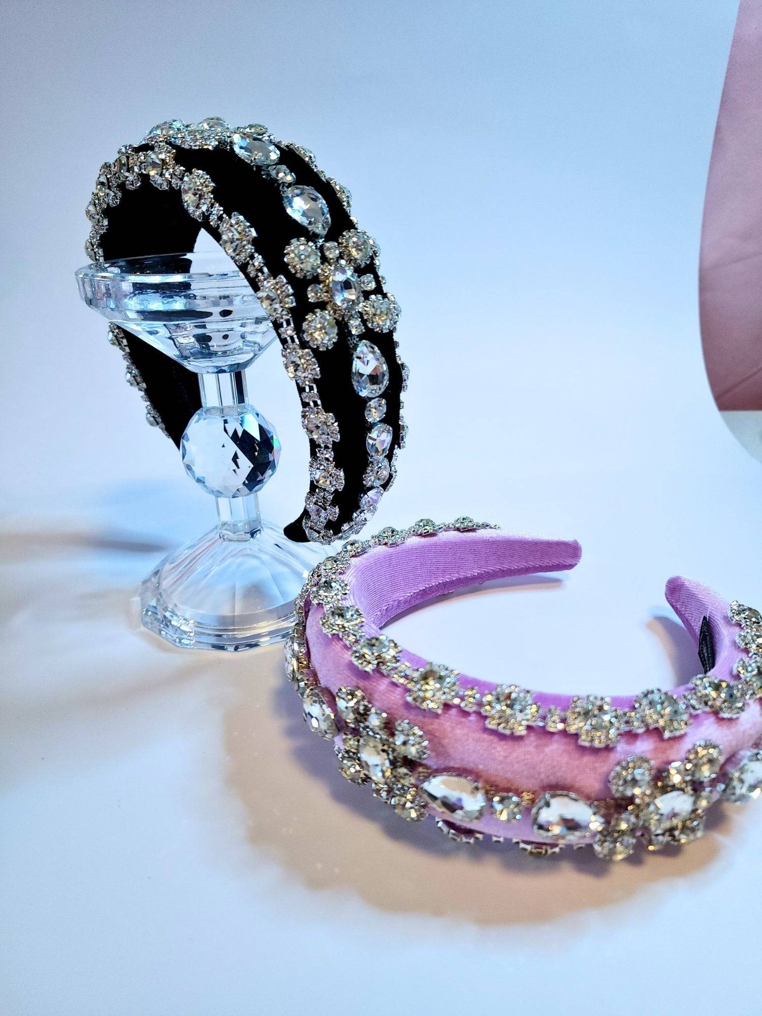 Both pink and black diamond goddess headbands displayed on a crystal stand.