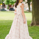 Pale pink floral apron maxi dress with ruffled cap sleeves and tiered skirt