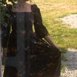 A woman in a floral cotton maxi dress standing outdoors on a sunny day.