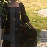 A woman in a floral cotton maxi dress standing outdoors on a sunny day.
