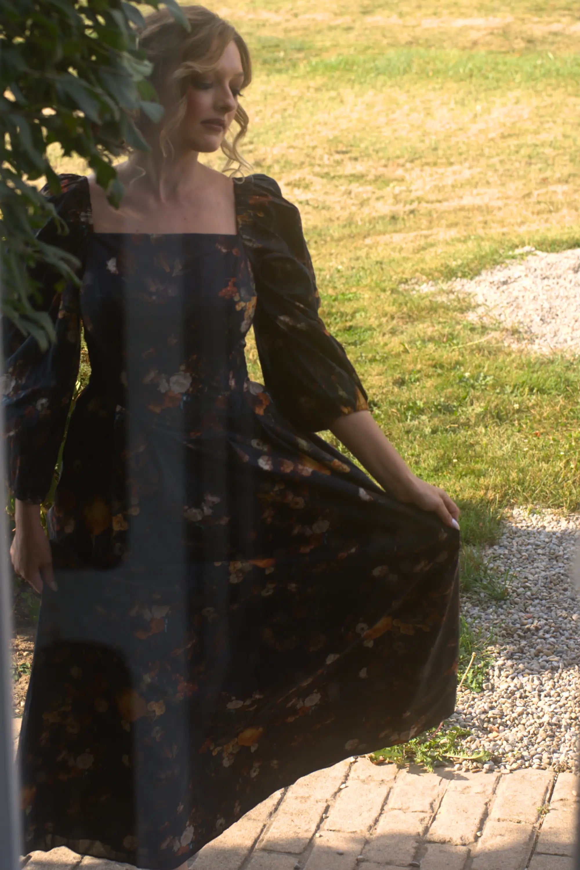 A woman in a floral cotton maxi dress standing outdoors on a sunny day.
