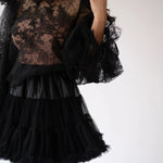 Close-up of The Eleanor Midnight Black Lace Top's intricate floral lace and sheer fabric paired with a tiered black skirt.