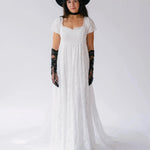 A woman wearing the Dauphine Lace Gown with black lace opera gloves and a black hat on a white background.