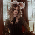 A woman in a black cotton dress with a decorative headpiece in a room with large windows.