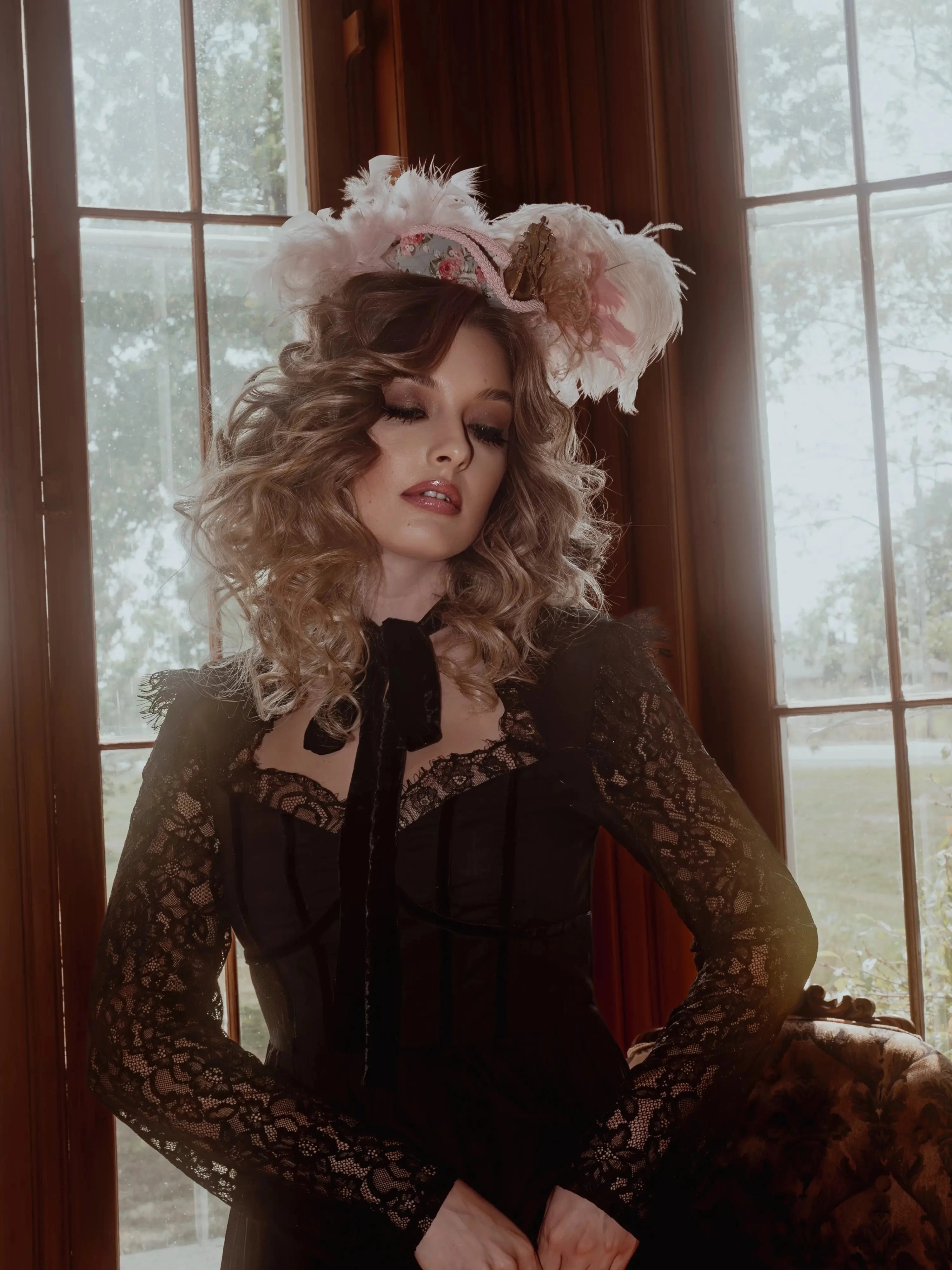 A woman in a black cotton dress with a decorative headpiece in a room with large windows.