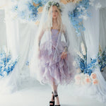 A woman wearing a tulip dress with a white tulle veil surrounded by floral arrangements.