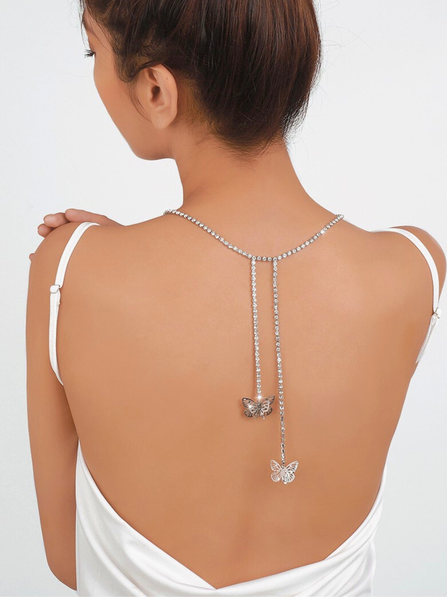 Delicate butterfly pendants on a bare back showcasing the Fairy Flutter Necklace