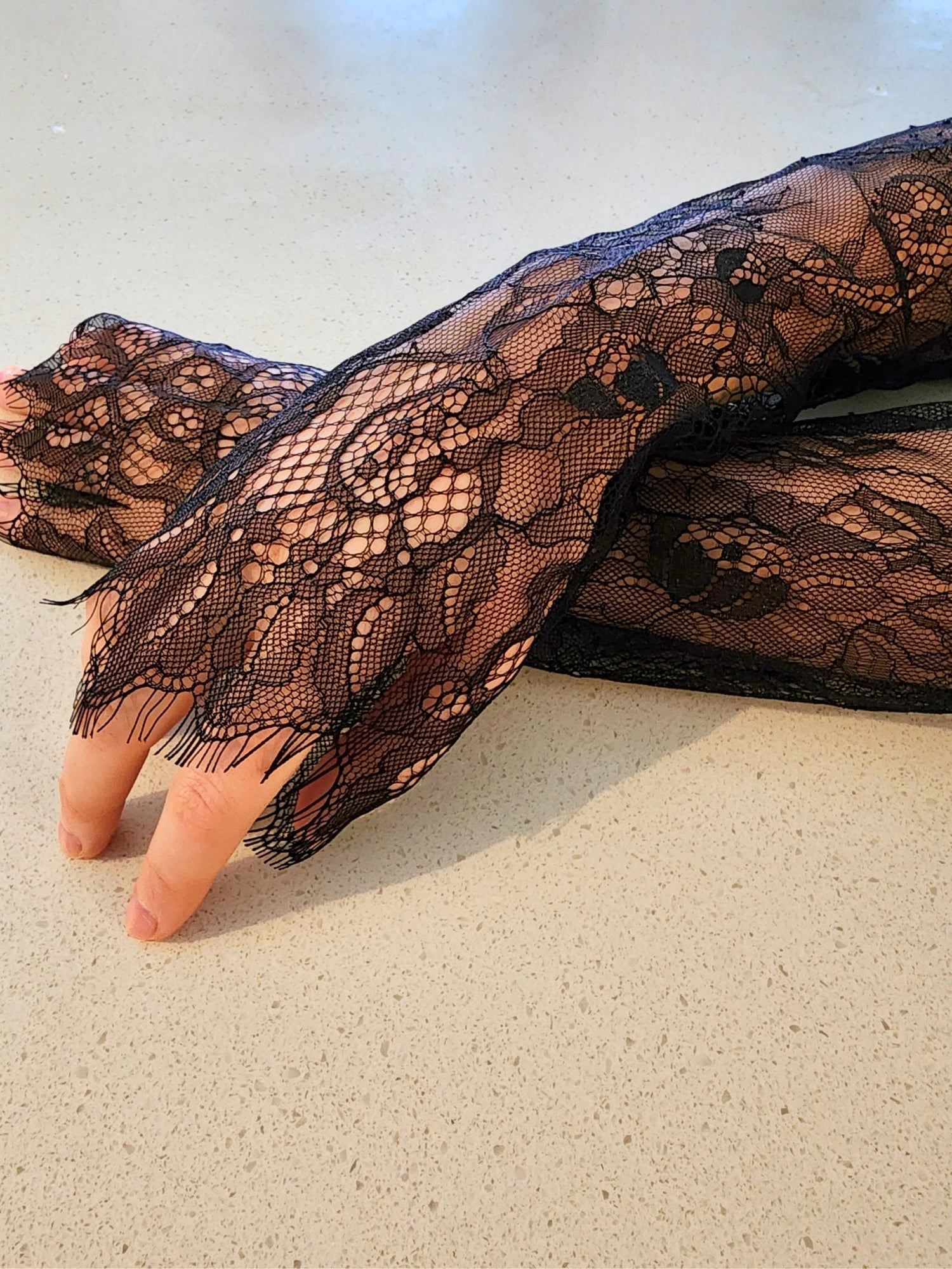 Delicate black lace glove on a hand, perfect with a gown or puff dress