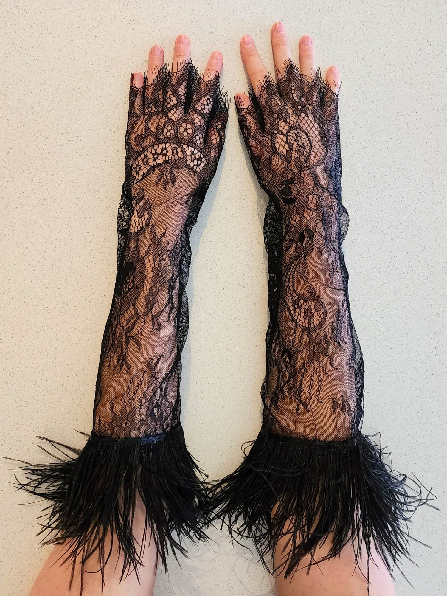 Pair of long black lace gloves with feathered cuffs, perfect for a gown or puff dress